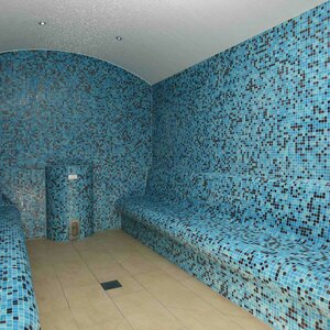 Innenansicht des Dampfbad im ATLANTIC Hotel Wilhelmshaven Dampfbad mit blauen Mosaikfliesen, gewölbter Decke und gefliesten Sitzbänken auf beiden Seiten.