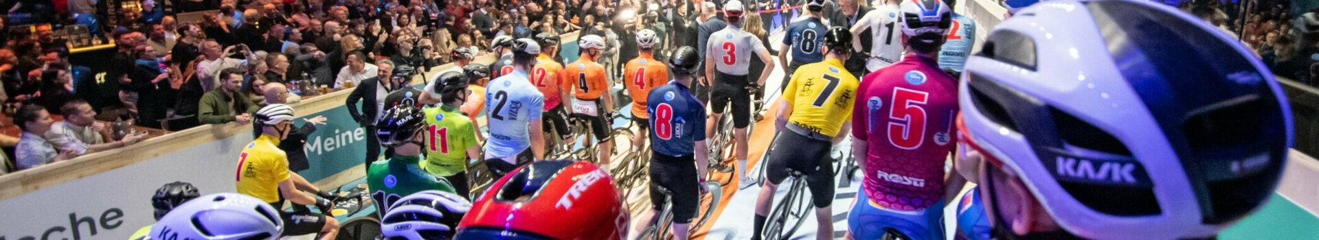 Bild der Fahrradfahrer bei den Sixdays vor dem Start auf der Fahrbahn, voller bunter Trikots und Helme