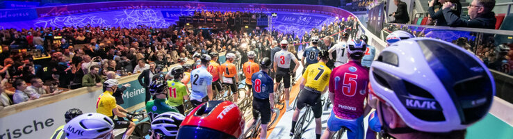 Bild der Fahrradfahrer bei den Sixdays vor dem Start auf der Fahrbahn, voller bunter Trikots und Helme
