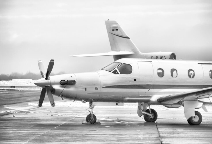 Propeller plane on a snow-covered runway, another plane in the background out of focus.