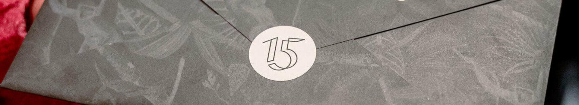 Hände halten einen eleganten Umschlag mit der Aufschrift "Experience Culinary Heights" im ATLANTIC Hotel Heidelberg.