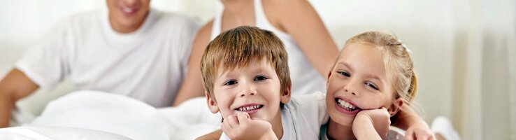 Family at the ATLANTIC Hotel Lübeck Family relaxing with a smile on a bed in the ATLANTIC Hotel Lübeck, bright and friendly atmosphere.