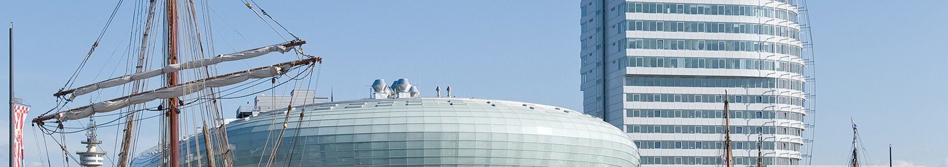 ATLANTIC Hotel Sail City in Bremerhaven, modern high-rise building on the waterfront with sailing ship in the foreground.