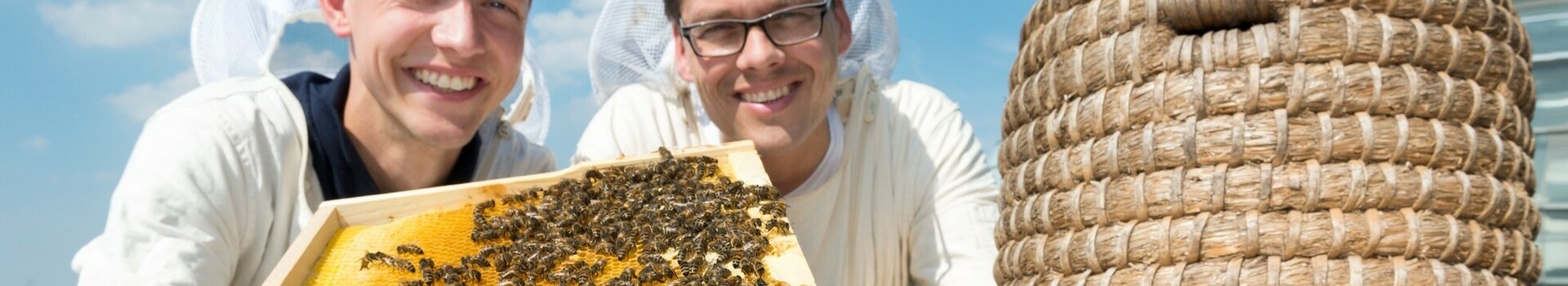 Imker auf dem Dach des ATLANTIC Hotel SAIL City in Bremerhaven mit ihren Bienen Zwei Imker in Schutzkleidung präsentieren eine Bienenwabe auf dem Dach des ATLANTIC Hotel Sail City.
