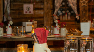 Gemütlicher, rustikaler Raum im ATLANTIC Grand Hotel Bremen, dekoriert mit karierten Lampions und gedeckten Tischen.