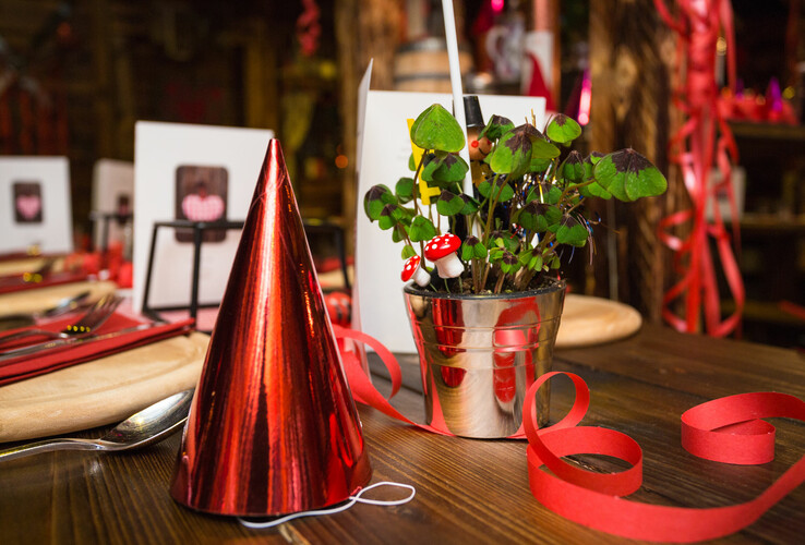Festively laid table with red party hat, shamrock in metal pot and decoration at the ATLANTIC Grand Hotel Bremen.