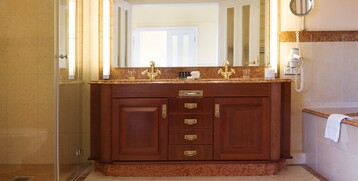 Elegantes Hotelbad mit Doppelwaschbecken, goldenen Armaturen und großer Spiegelwand im ATLANTIC Grand Hotel Travemünde.