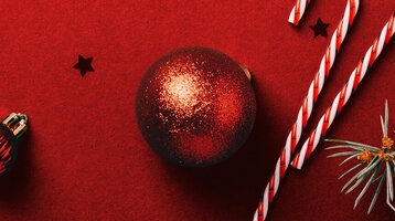 Weihnachtlicher Hintergrund mit Christbaumkugeln, Zuckerstange und Tannenzweigen