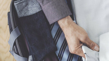 Gepackter Koffer mit Hemd, Krawatten, Schuhen, Uhr und Brieftasche auf Holzboden im ATLANTIC Grand Hotel Bremen.