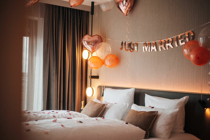 Hotel room with "Just Married" decoration, heart balloons and rose petals on the bed at the ATLANTIC Hotel Heidelberg.