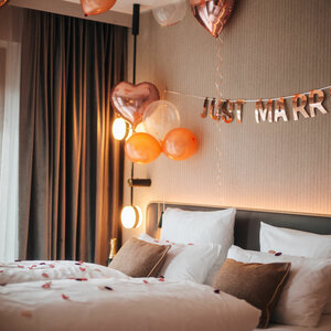Hotel room with "Just Married" decoration, heart balloons and rose petals on the bed at the ATLANTIC Hotel Heidelberg.