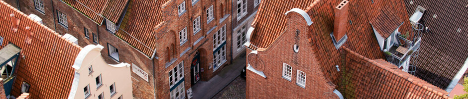 Luftaufnahme historischer Backsteinhäuser mit roten Ziegeldächern in Lübecks Altstadt.