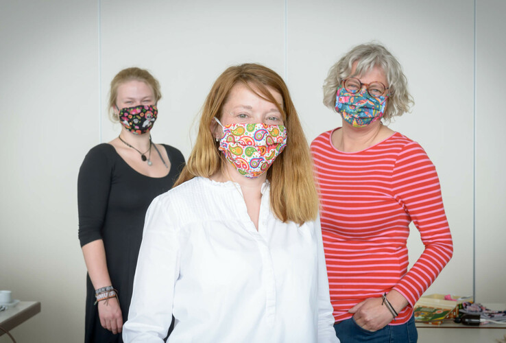 Drei Frauen mit bunten Masken lächeln in die Kamera, im Konferenzraum des ATLANTIC Hotel Sail City.