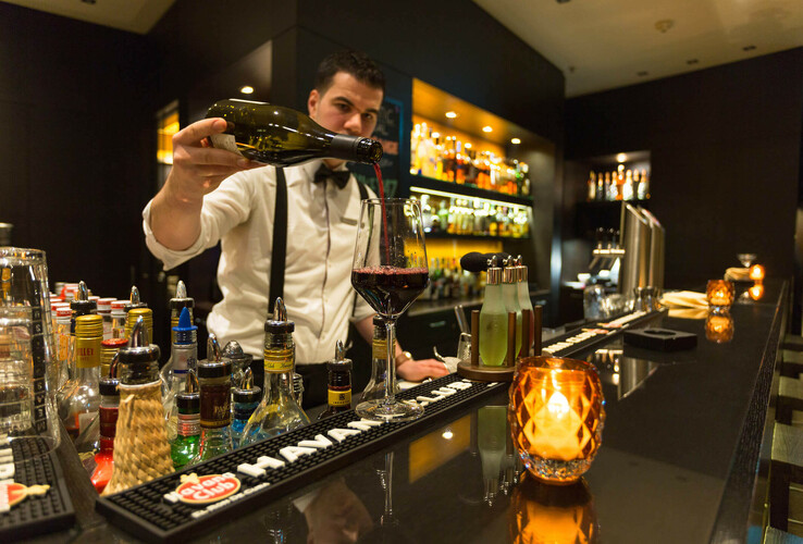Barkeeper schenkt Wein in stilvoller Hotelbar des ATLANTIC Grand Hotel Bremen ein.