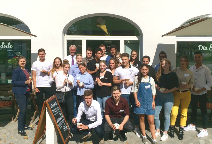 Gruppe von Menschen genießt Eis vor einer Eisdiele bei sonnigem Wetter.