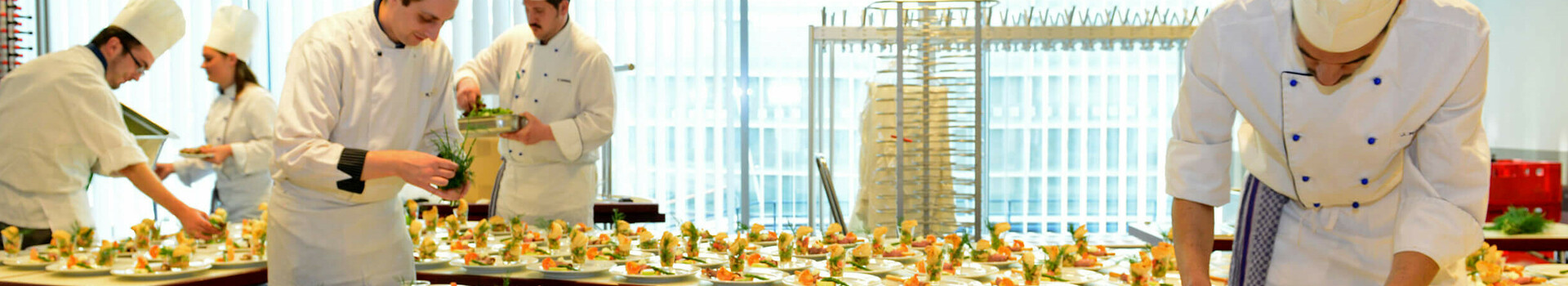 Veranstaltung im ATLANTIC Hotel SAIL City Bremerhaven Köche richten zahlreiche Teller mit kunstvoll angerichteten Vorspeisen in der Küche des ATLANTIC Hotel Sail City an.