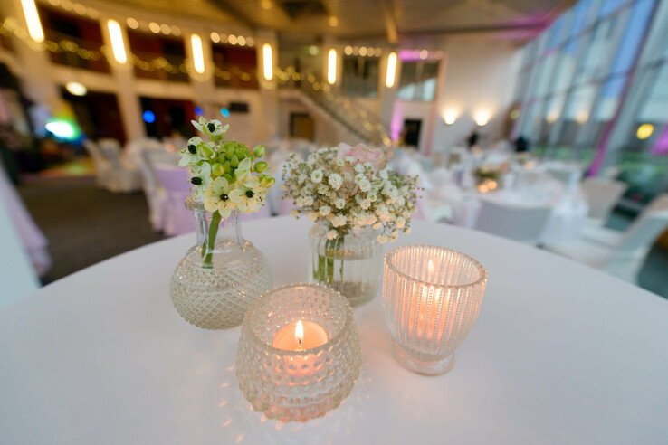 Tischdekoration mit Blumen und Kerzen in stilvollem, beleuchtetem Veranstaltungsraum des ATLANTIC Hotel Universum.
