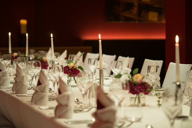 Elegant, festively laid table with candles, flower arrangements and folded napkins at the ATLANTIC Hotel Kiel.