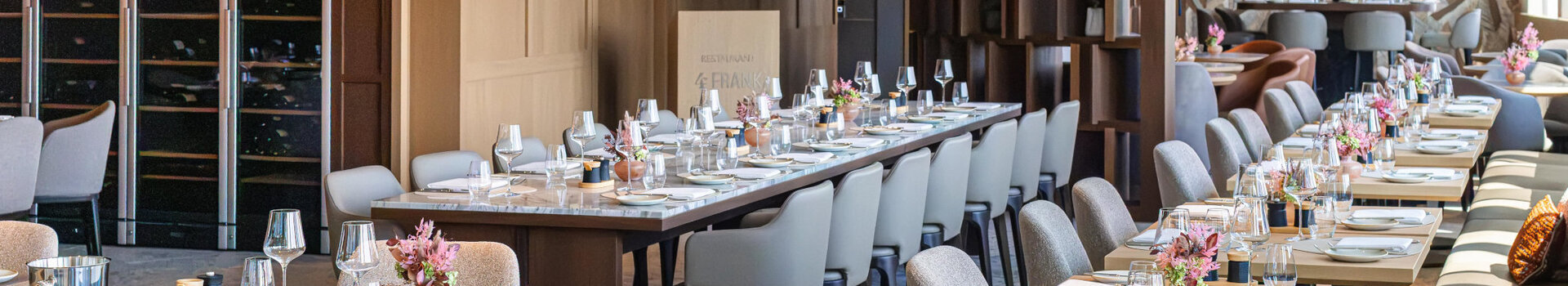 The 4FRANK restaurant, with a festive table setting and vases of flowers.