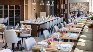 Das Restaurant 4FRANK mit festlichem Gedeck und Blumenvasen. 