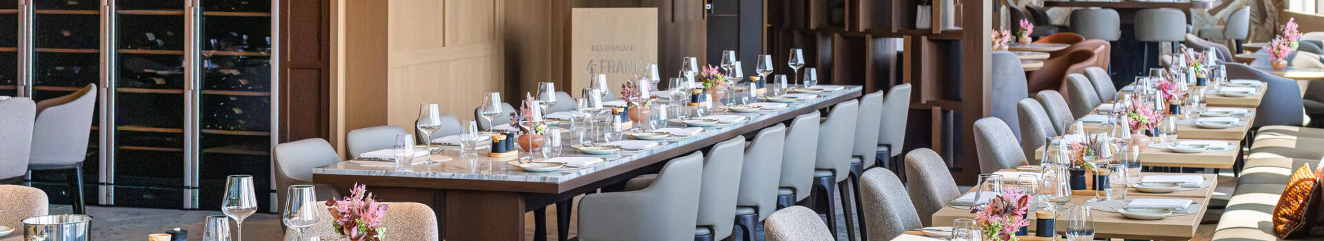 Das Restaurant 4FRANK mit festlichem Gedeck und Blumenvasen.