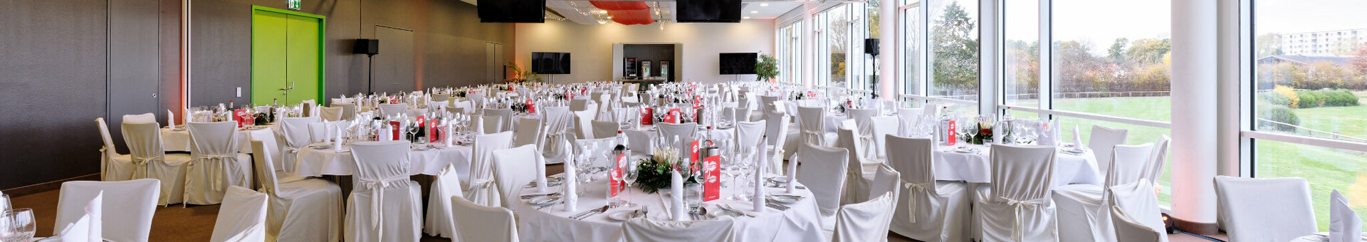 Elegant banquet hall in the ATLANTIC Hotel Galopprennbahn, Bremen, with white-clothed tables and a large window front.