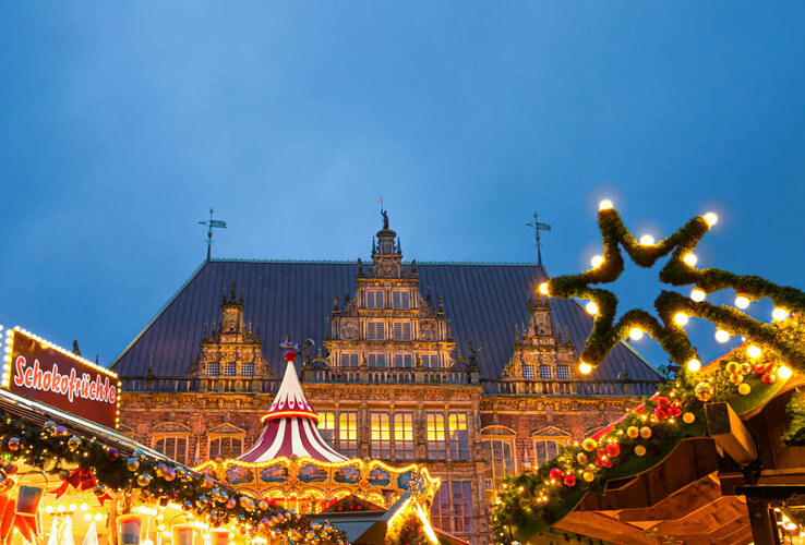 Picture of the Bremen city hall and dark sky with the christmas market in front of it
