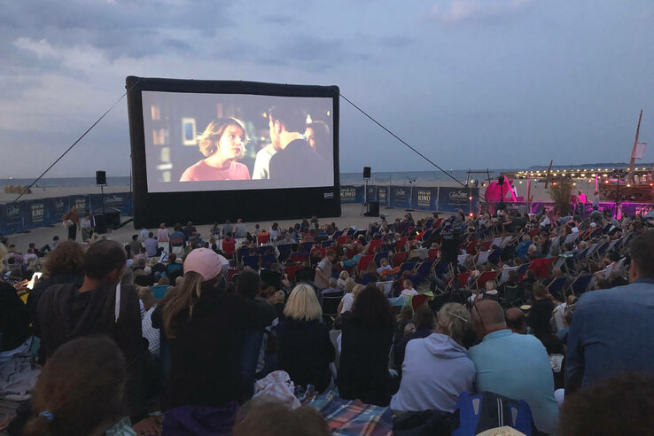 Open-Air-Kino am Strand mit großer Leinwand und Publikum in Liegestühlen, Abendstimmung am ATLANTIC Grand Hotel Travemünde.