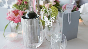 Elegant gedeckter Tisch mit Blumen, Weingläsern und Weinflasche im ATLANTIC Hotel Galopprennbahn Bremen.