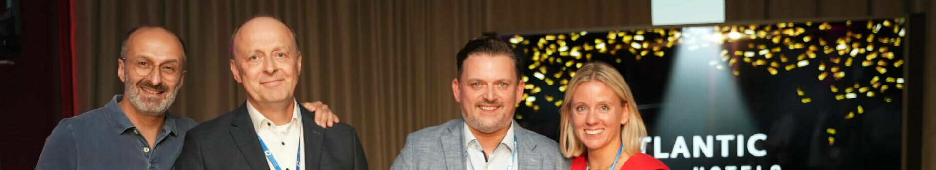 HSMA Social Media Award | ATLANTIC Hotel Sail City Vier Personen bei einer Preisverleihung im ATLANTIC Hotel, eine hält Blumen, eine andere eine Urkunde.