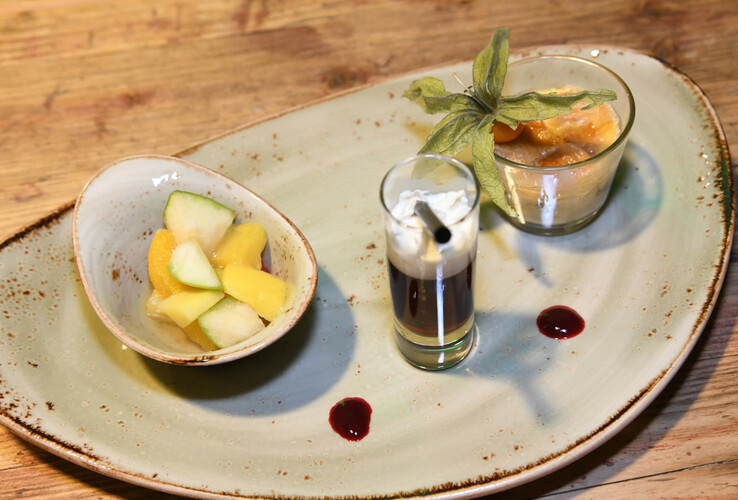 Dessertplatte mit Obstsalat, Espresso im Glas und Creme-Dessert im Glas, dekoriert mit Physalis.