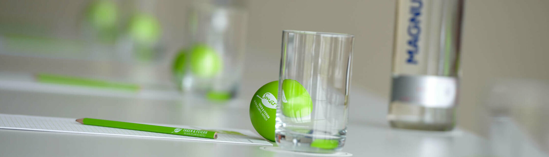 Meeting set-up at the ATLANTIC Hotels Conference table with green balls, glasses, pens and a water bottle, stylishly arranged.