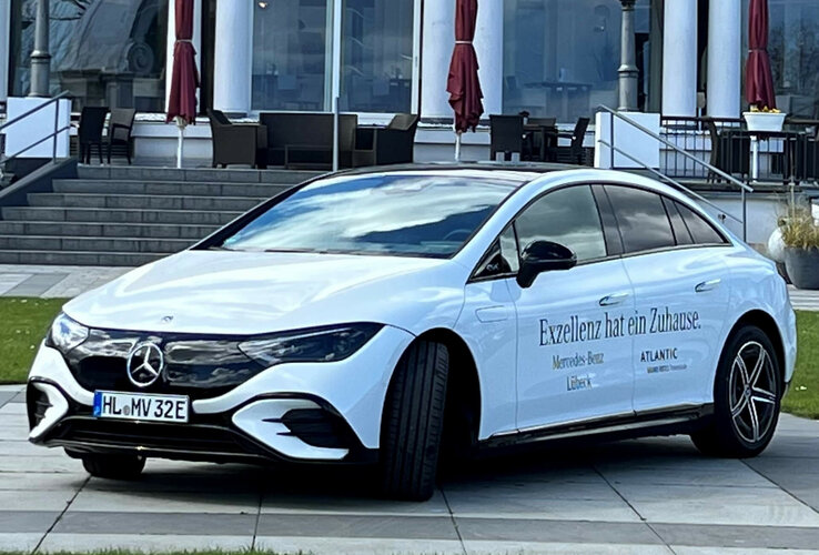Weißes Elektroauto vor dem ATLANTIC Grand Hotel Travemünde, mit Schriftzug "Exzellenz hat ein Zuhause".
