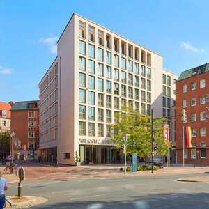 Modern façade of the ATLANTIC Grand Hotel Bremen on a sunny day, with large windows and urban surroundings.