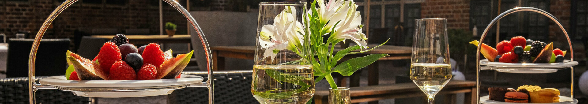 Obst und Macarons auf Etageren, Blumen und Weingläser auf einer Terrasse des ATLANTIC Grand Hotel Bremen.