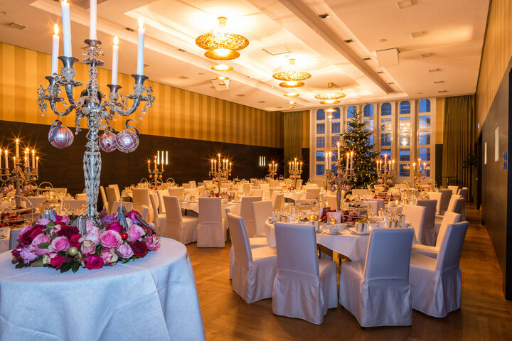 Elegant, festively decorated banquet hall with candlesticks, white tablecloths and a Christmas tree at the ATLANTIC Grand Hotel Bremen.