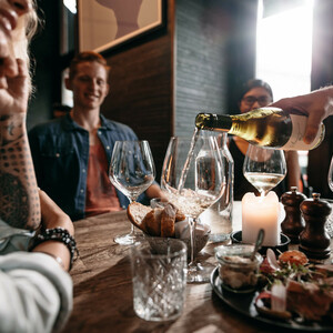ATLANTIC Hotel Münster Essen & Trinken Gemütliche Runde im ATLANTIC Hotel Münster: Wein wird eingeschenkt, Kerzenlicht, Brot und Vorspeisen auf dem Tisch.