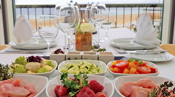 Eleganter Tisch mit frischen Zutaten und Meerblick im ATLANTIC Grand Hotel Travemünde.