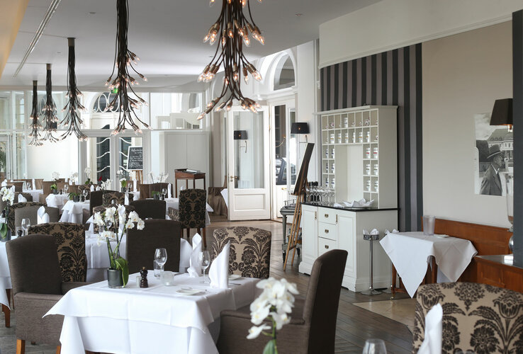 Elegantes Hotelrestaurant mit stilvoll gedeckten Tischen, modernen Kronleuchtern und floralen Dekorationen.