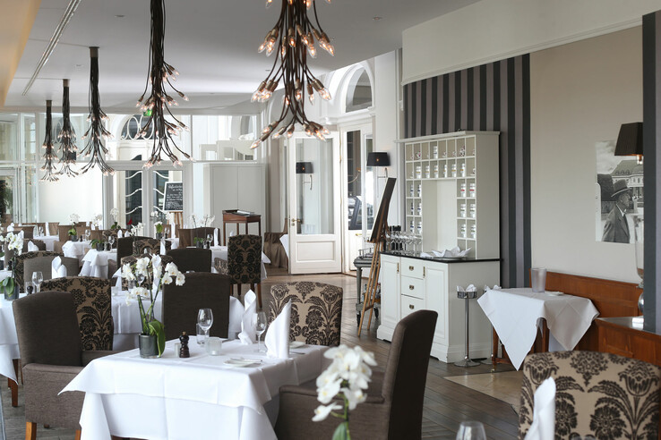 Elegantes Hotelrestaurant mit stilvoll gedeckten Tischen, modernen Kronleuchtern und floralen Dekorationen.