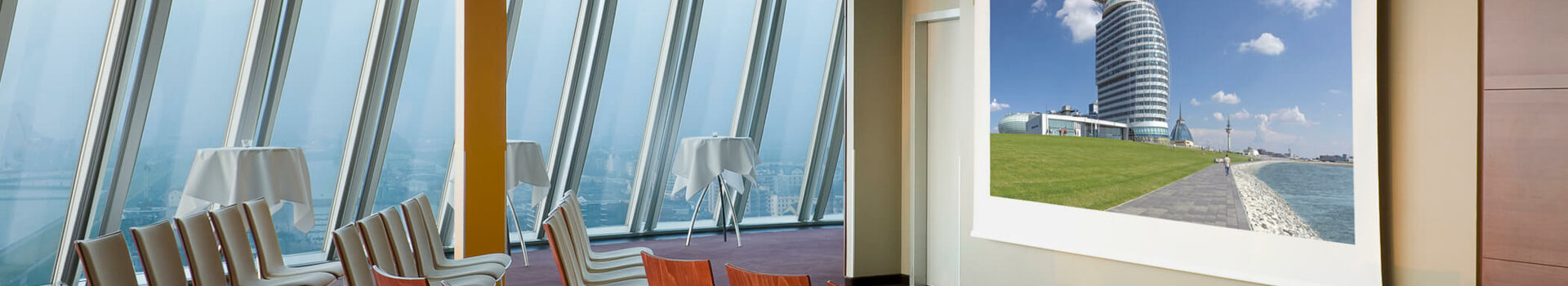 Tagen in der Captain´s Lounge des ATLANTIC Hotel Sail City Moderner Konferenzraum im ATLANTIC Hotel Sail City mit Reihenstühlen und Blick auf eine Präsentationsleinwand.