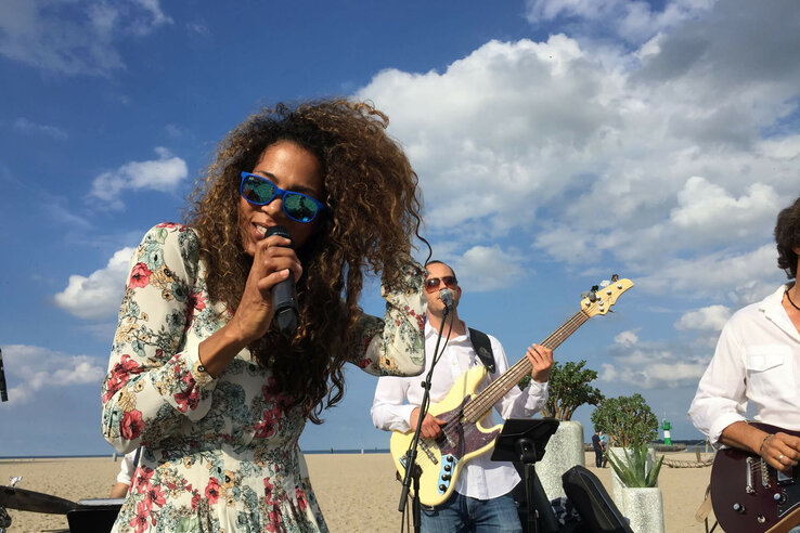 Eine Band spielt am Strand von Travemünde unter blauem Himmel.