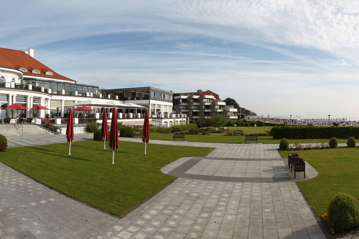 Das ATLANTIC Grand Hotel Travemünde mit gepflegtem Garten, Terrasse und Blick auf die Ostsee.
