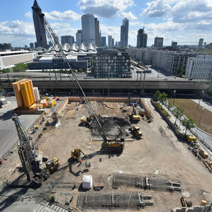 Baustelle vom ATLANTIC Hotel Frankfurt Blick auf eine große Baustelle mit Kränen und Maschinen vor einer städtischen Skyline bei sonnigem Wetter.