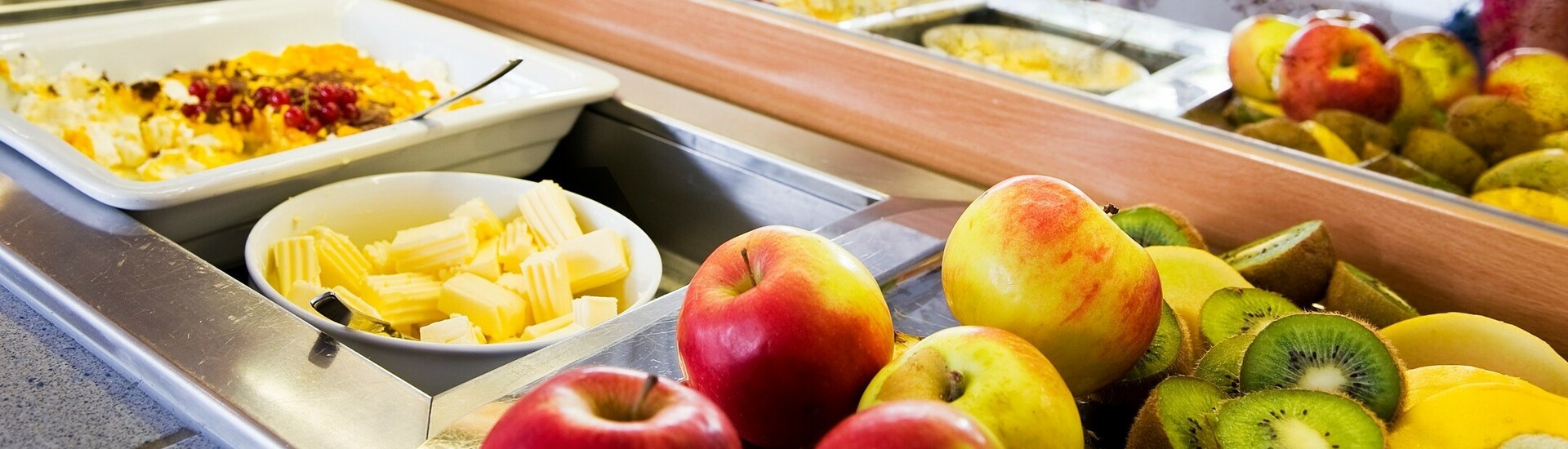 Breakfast buffet with fresh fruit, cheese and muesli at the ATLANTIC Hotel Vegesack, Bremen. Guests at the table in the background.
