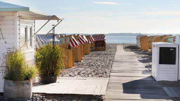 Beach Travemünde Beach with wooden walkway, beach chairs and sea view at the ATLANTIC Grand Hotel Travemünde.