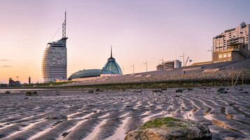 Bremerhaven Trailer | ATLANTIC Hotel Sail City ATLANTIC Hotel Sail City in Bremerhaven bei Sonnenuntergang, mit Wattlandschaft im Vordergrund.