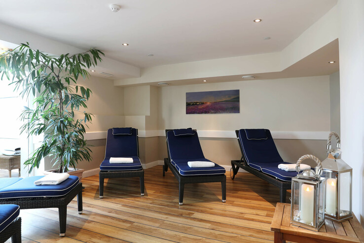 Heller Ruheraum mit blauen Liegen, Pflanzen und Kerzenlaternen im ATLANTIC Grand Hotel Travemünde.