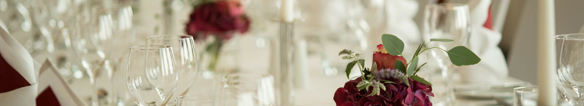 Festive table in function room Hörn in the ATLANTIC Hotel Kiel Elegant, festively laid table with white candles, wine glasses and red flower arrangements at the ATLANTIC Hotel Kiel.
