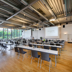 Moderner Konferenzraum im ATLANTIC Hotel Universum mit großen Fenstern und Tagungstischen.